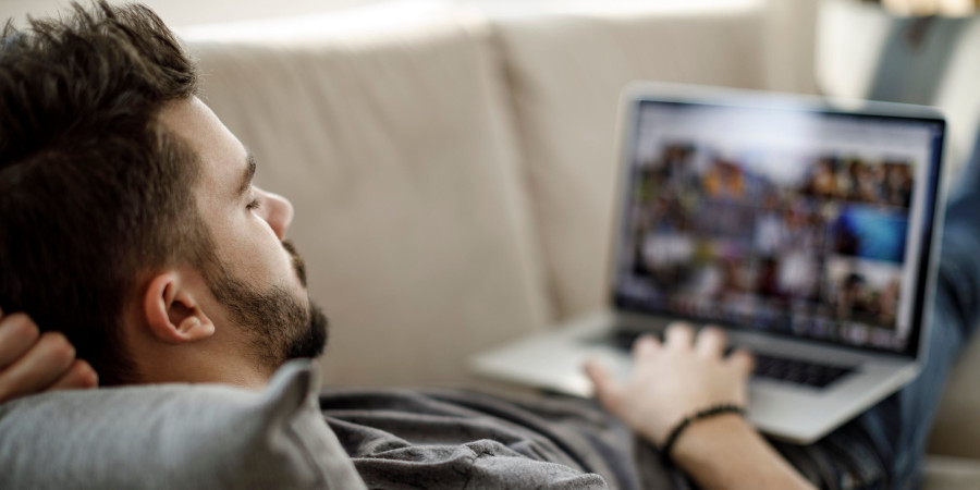 Un homme sur son canapé en train de visionner des contenus gaming et qui a pris la peine de baisser la qualité des vidéos pour préserver la planète.