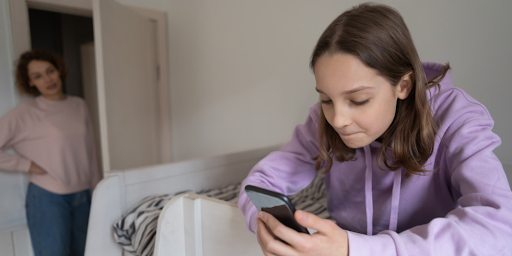 Une mère regardant sa fille en train d’utiliser un smartphone