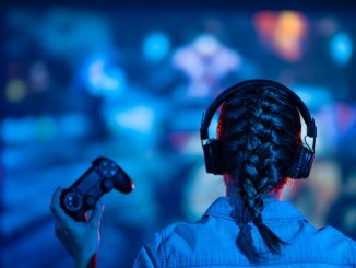 Une jeune femme jouant a des jeux video : manette a la main et casque aux oreilles