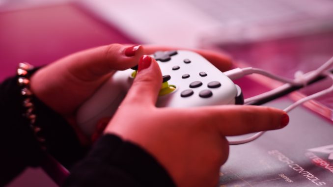 Crise des refugies : mains d’une femme tenant une manette de jeux video