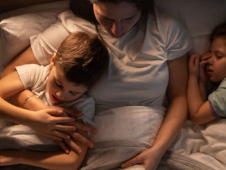 Une mère lisant un livre à ses bambins, une activité permettant de modérer l’usage des écrans chez les enfants.