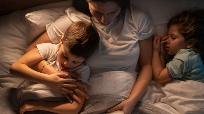 Une mère lisant un livre à ses bambins, une activité permettant de modérer l’usage des écrans chez les enfants.