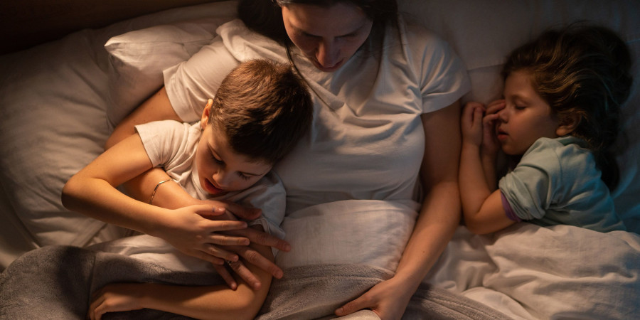 Une mère lisant un livre à ses bambins, une activité permettant de modérer l’usage des écrans chez les enfants.