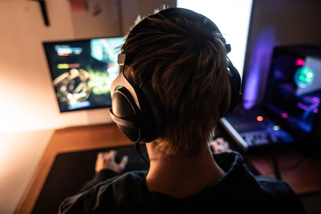 Vue de dos d’un gamer jouant a un jeu video portant un casque audio