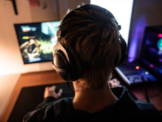 Vue de dos d’un gamer jouant a un jeu video portant un casque audio