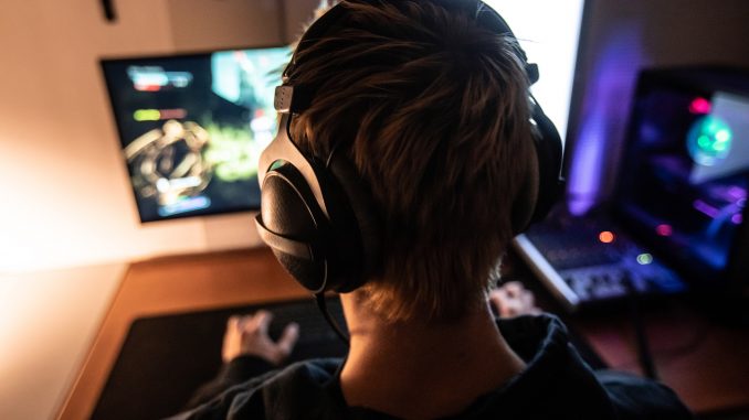 Vue de dos d’un gamer jouant a un jeu video portant un casque audio