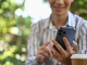 Une femme devant son ordinateur utilise son smartphone