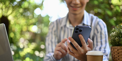 Une femme devant son ordinateur utilise son smartphone