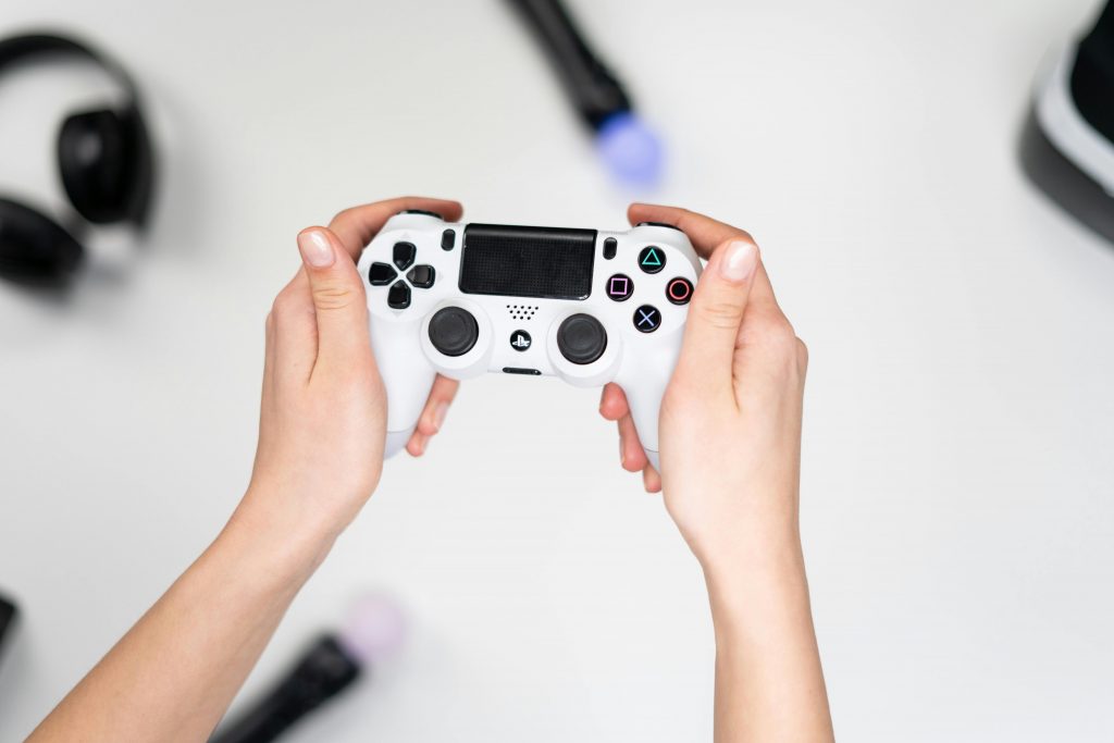 Un joueur tenant une manette de PlayStation grise dans ses mains.