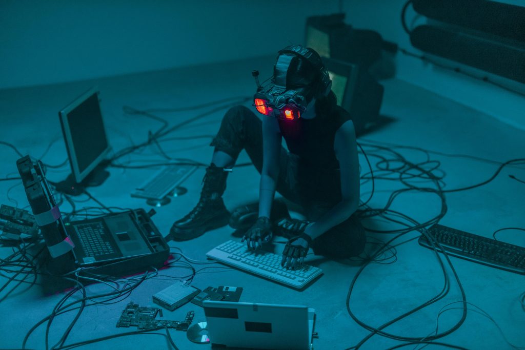 Une femme assise par terre, utilisant des ordinateurs pour un projet technologique.