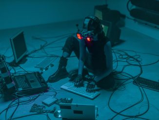 Une femme assise par terre, utilisant des ordinateurs pour un projet technologique.