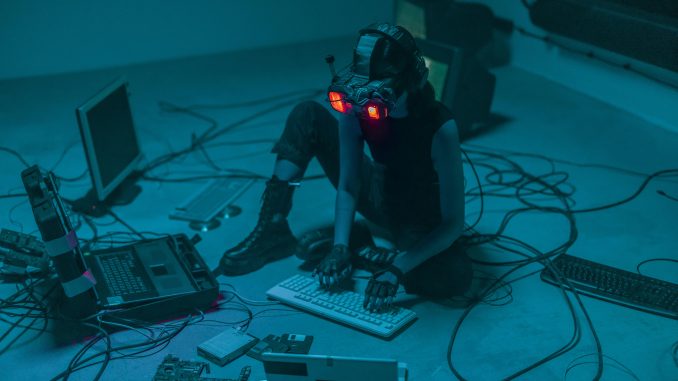 Une femme assise par terre, utilisant des ordinateurs pour un projet technologique.