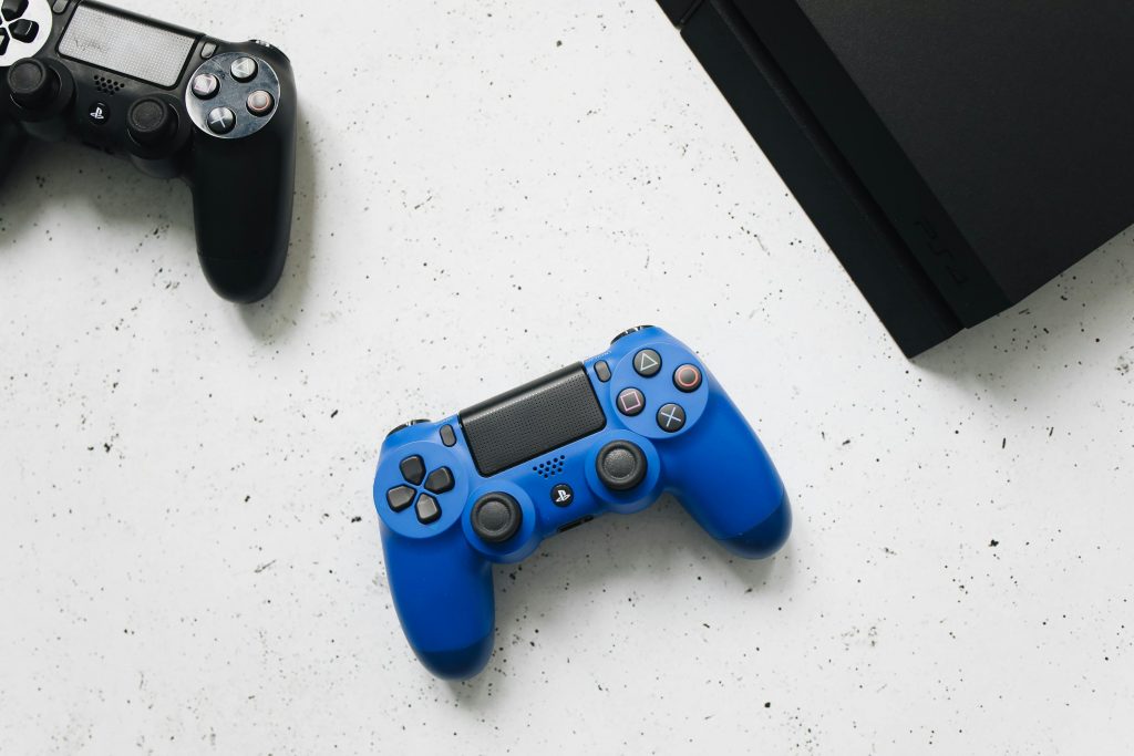 Deux manettes de jeu vidéo et une console PlayStation côte-à-côte.