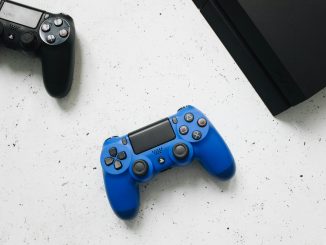 Deux manettes de jeu vidéo et une console PlayStation côte-à-côte.