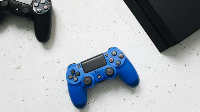 Deux manettes de jeu vidéo et une console PlayStation côte-à-côte.