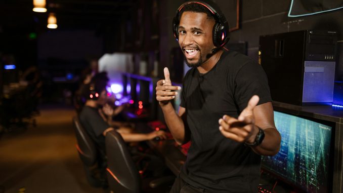 Un homme souriant portant un casque noir, écoutant de la musique de jeux vidéo.