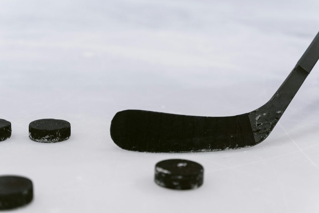 Vue rapprochée d’un palet de hockey et d’un bâton sur la glace.