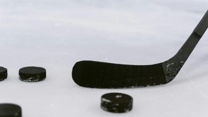 Vue rapprochée d’un palet de hockey et d’un bâton sur la glace.