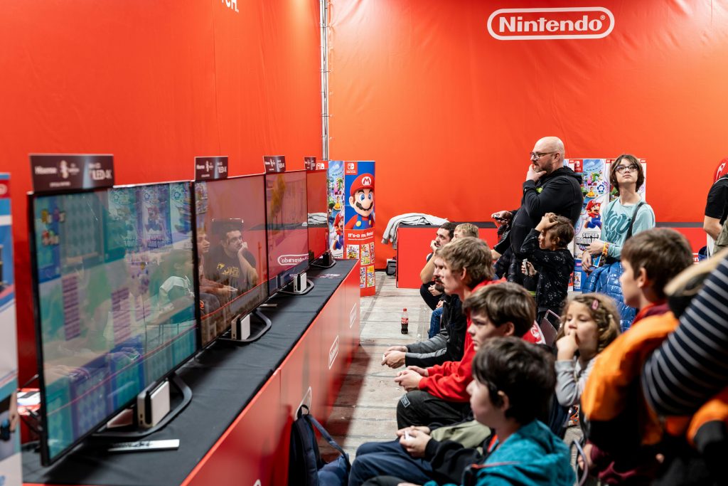 Des visiteurs au salon Paris Games Week 2024, testant des jeux vidéo au stand de Nintendo.