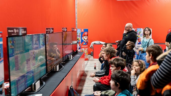 Des visiteurs au salon Paris Games Week 2024, testant des jeux vidéo au stand de Nintendo.