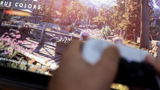 Un gamer avec sa manette, en train de jouer au jeu « Life is Strange » dans la version « True Colors ».