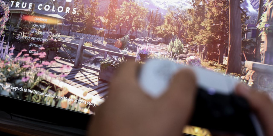 Un gamer avec sa manette, en train de jouer au jeu « Life is Strange » dans la version « True Colors ».