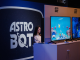 Un joueur interagit avec Astro Bot, plusieurs écrans montrent des scènes du jeu.