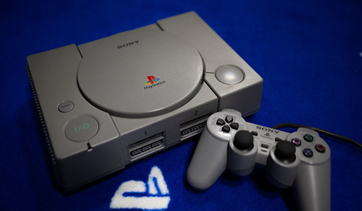 Une console PlayStation grise avec sa manette classique sur une table.