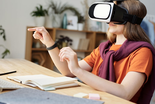 Une jeune fille portant des lunettes de réalité virtuelle avec un cahier et un stylo sur la table